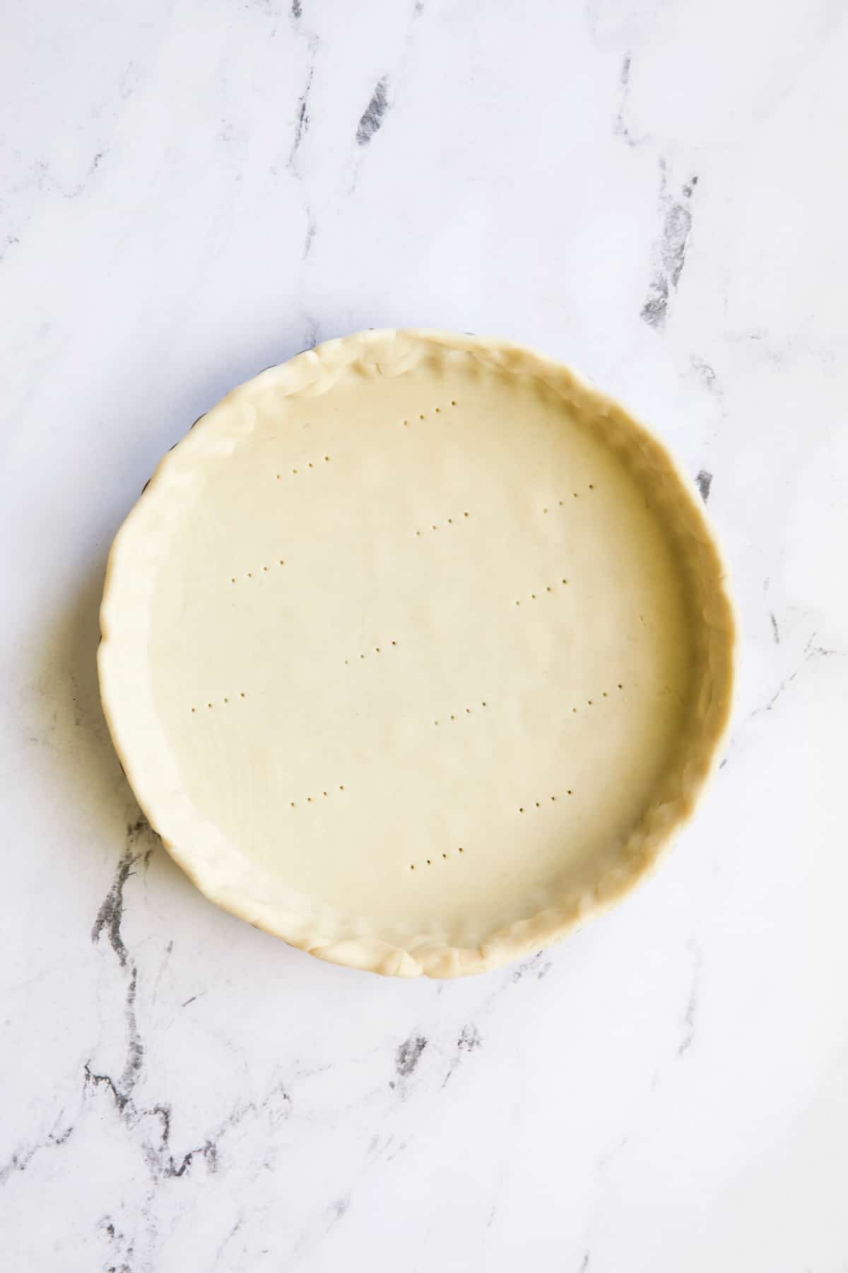 Photo of unbaked pie crust on marble surface.