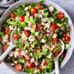 Photo of Italian Chopped Salad with Chicken in gray bowl with serving utensils.