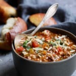Photo of a bowl of Southwestern Stuffed Pepper Soup on blue background with bread.