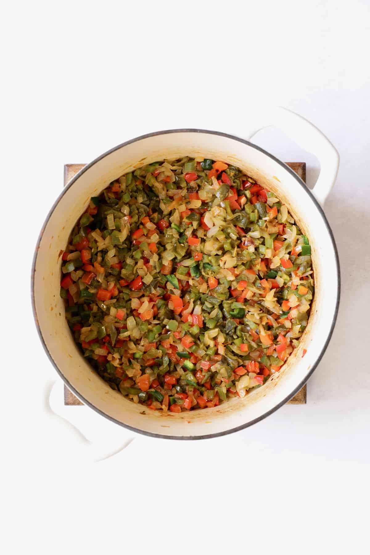 Photo of cooked onions and peppers in white Dutch oven.