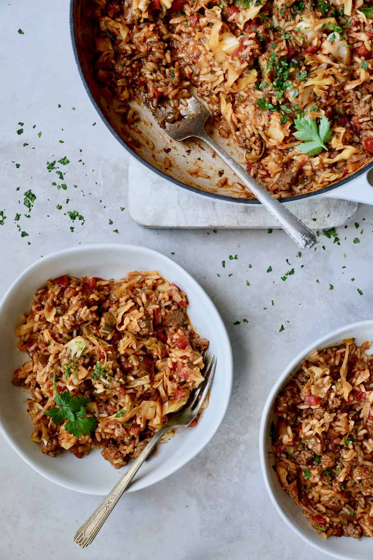 Photo of Unstuffed Chorizo Cabbage Roll Skillet in two serving bowls with some served up from white enamel skillet.