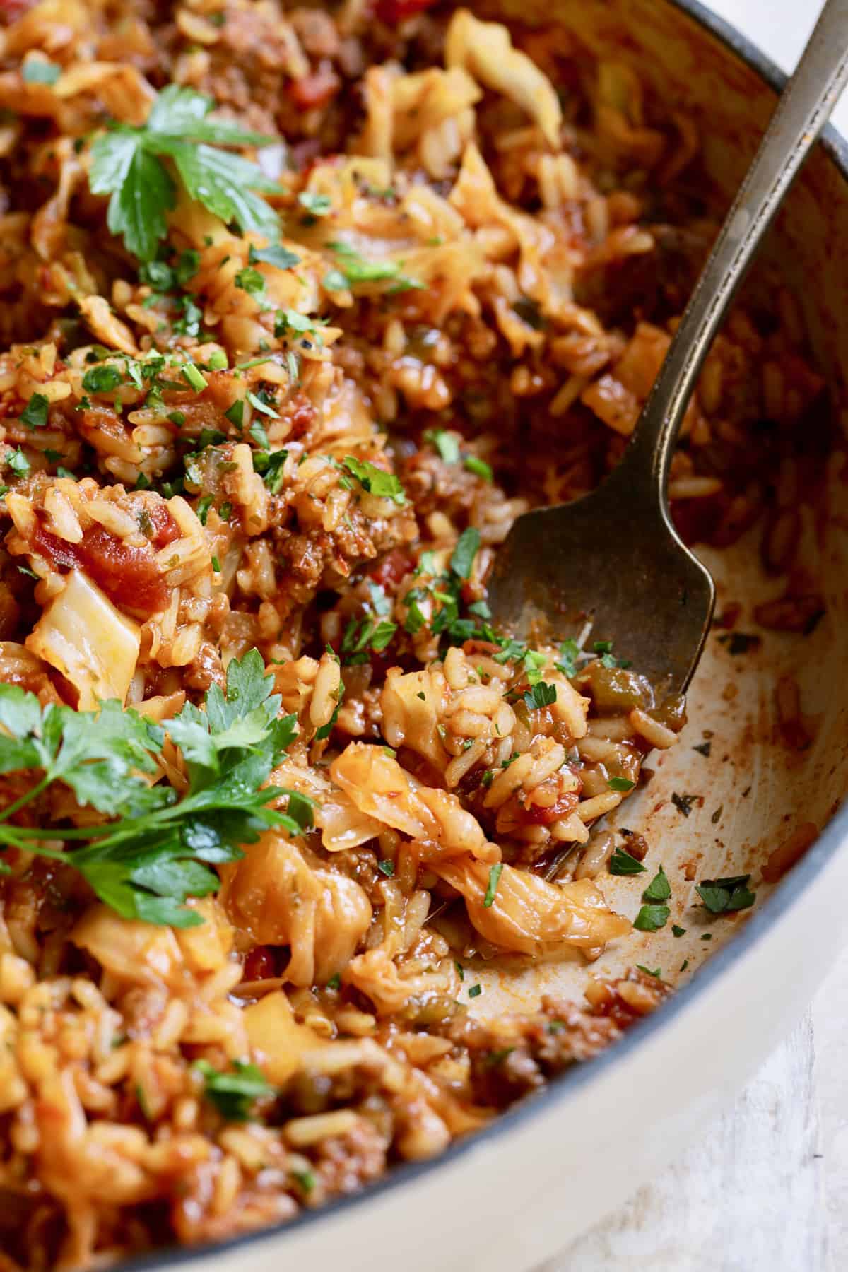 Close-up photo of Unstuffed Chorizo Cabbage Roll Skillet with serving fork garnished with parsley.