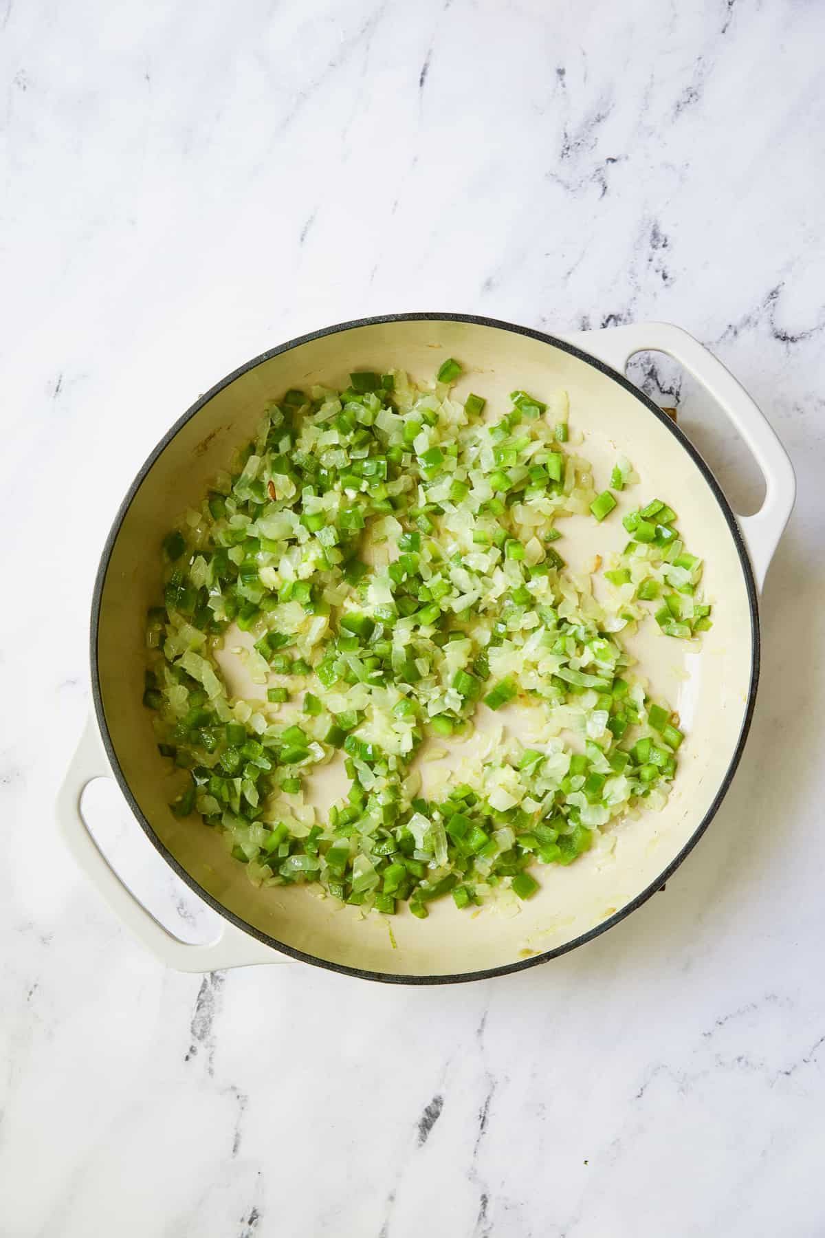 Photo of cooked onion and pepper in white enamel skillet.