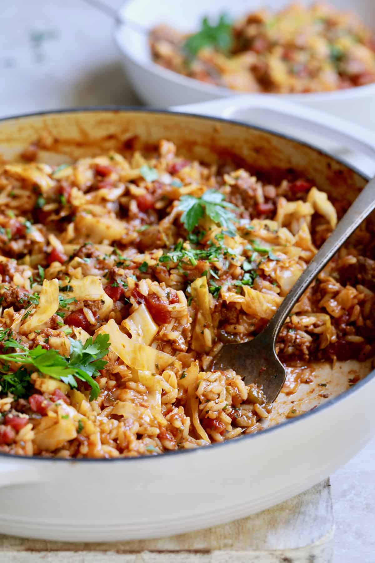 Photo of Unstuffed Chorizo Cabbage Roll Skillet being served from white enamel skillet.