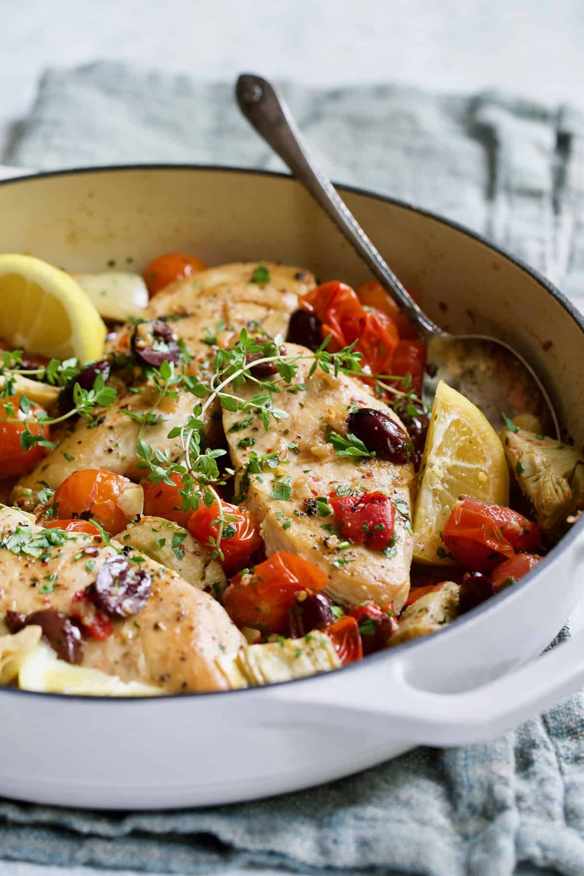 Easy Skillet Mediterranean Chicken in white enamel skillet on blue napkin.