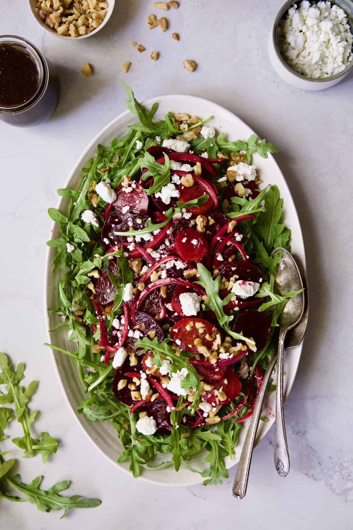 Roasted Beet Salad with Walnuts Goat Cheese and Honey Balsamic Dressing with dressing, walnuts and goat cheese in small bowls.