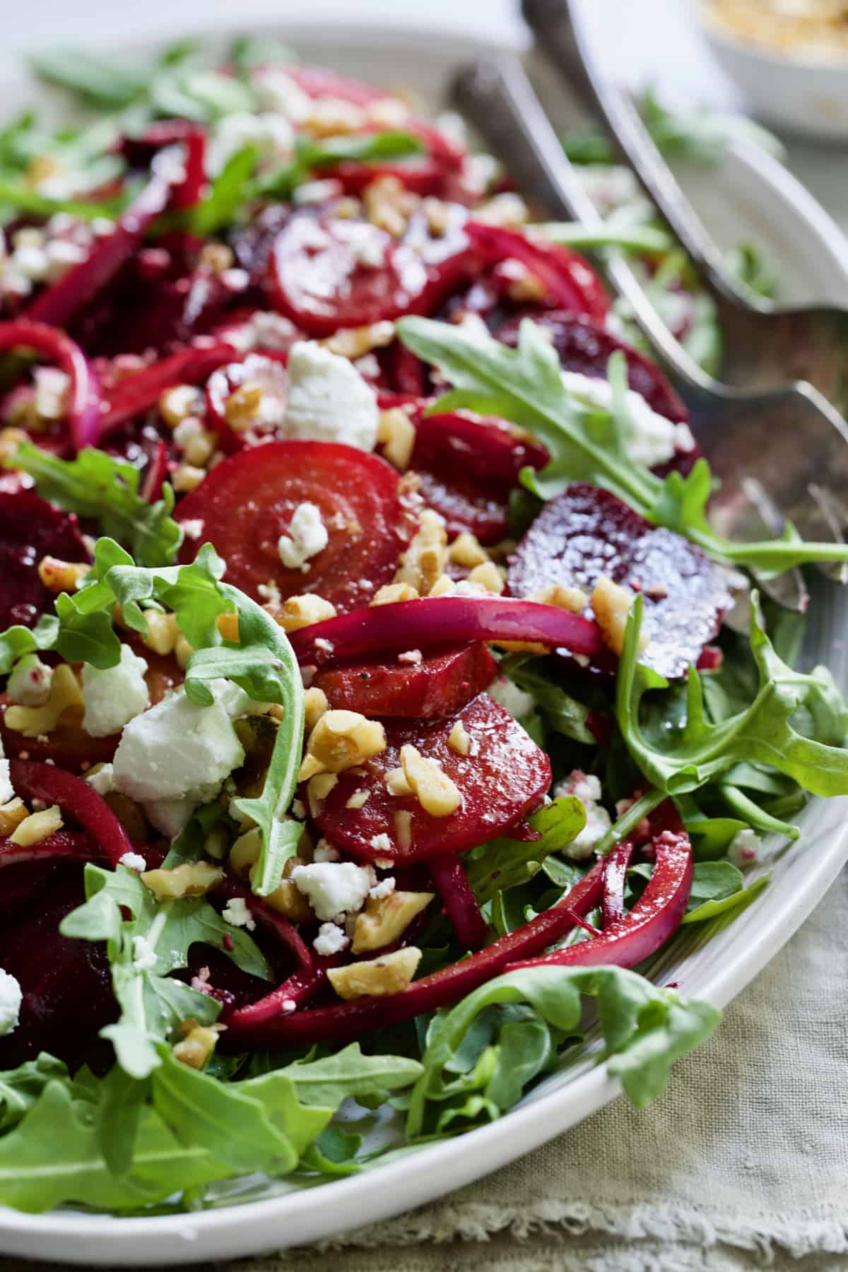 Roasted Beet Salad with Walnuts Goat Cheese and Honey Balsamic Dressing on white platter with beige napkin.