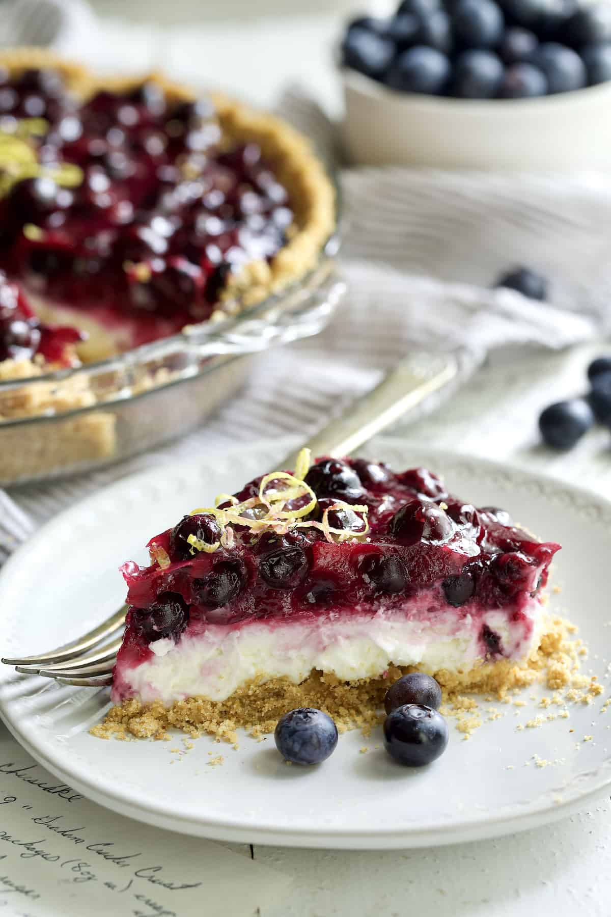 Close-up photo of a piece ofd Blueberry Cream Cheese Pie on white plate.