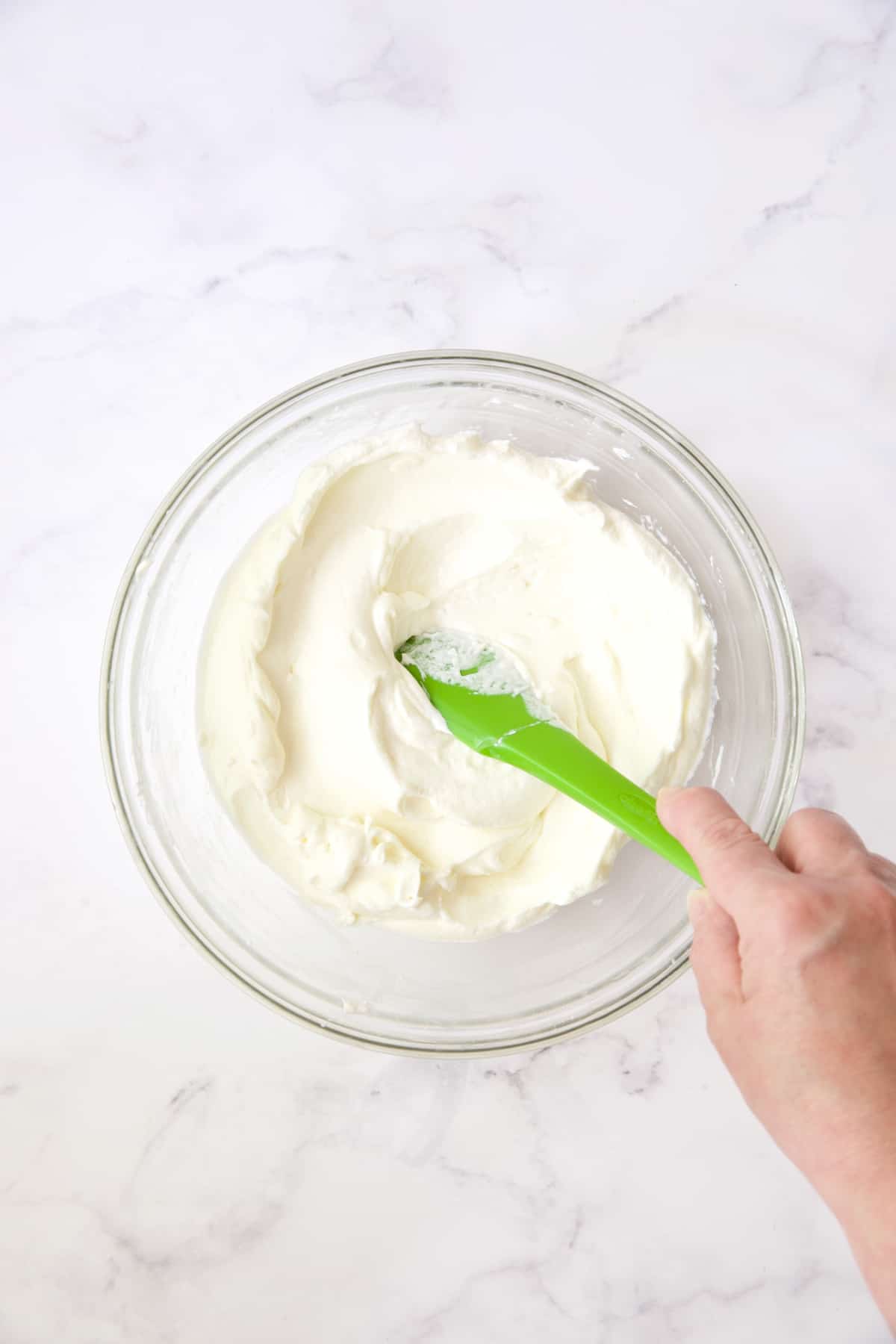 Process photo of cream cheese and whipped cream being folded together.