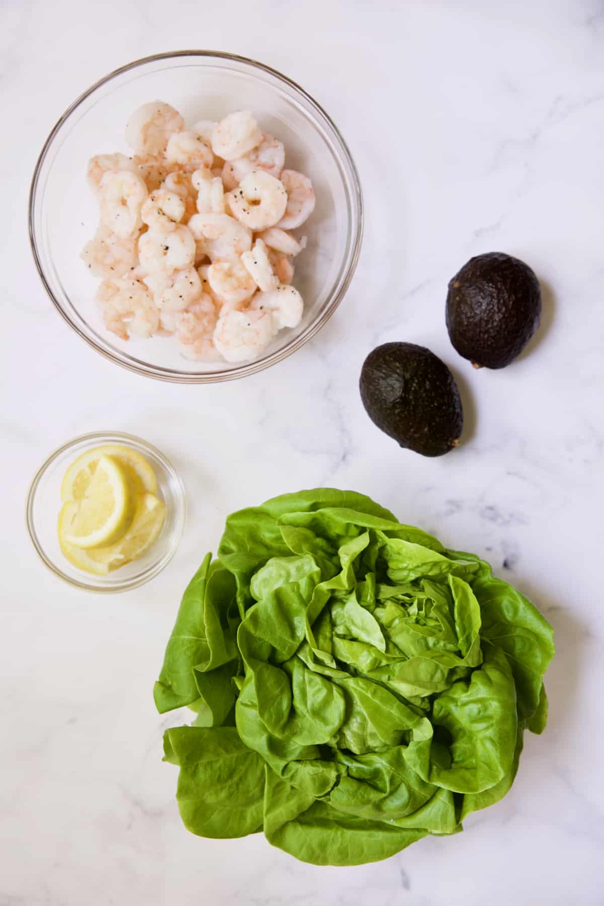 Photo of cooked shrimp, lemon wedges, avocados and lettuce.