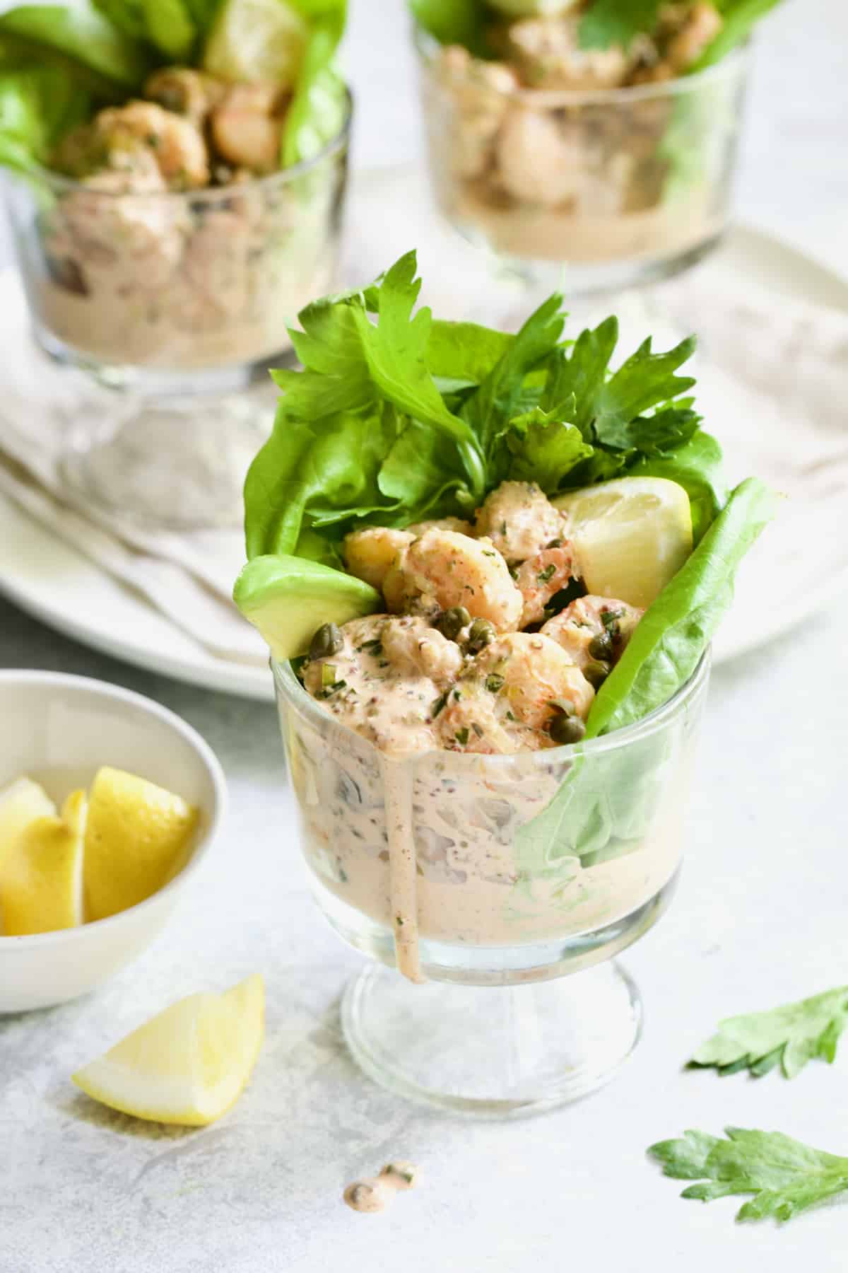 Sriracha Shrimp Remoulade Cocktail with lemon wedge and celery leaves.