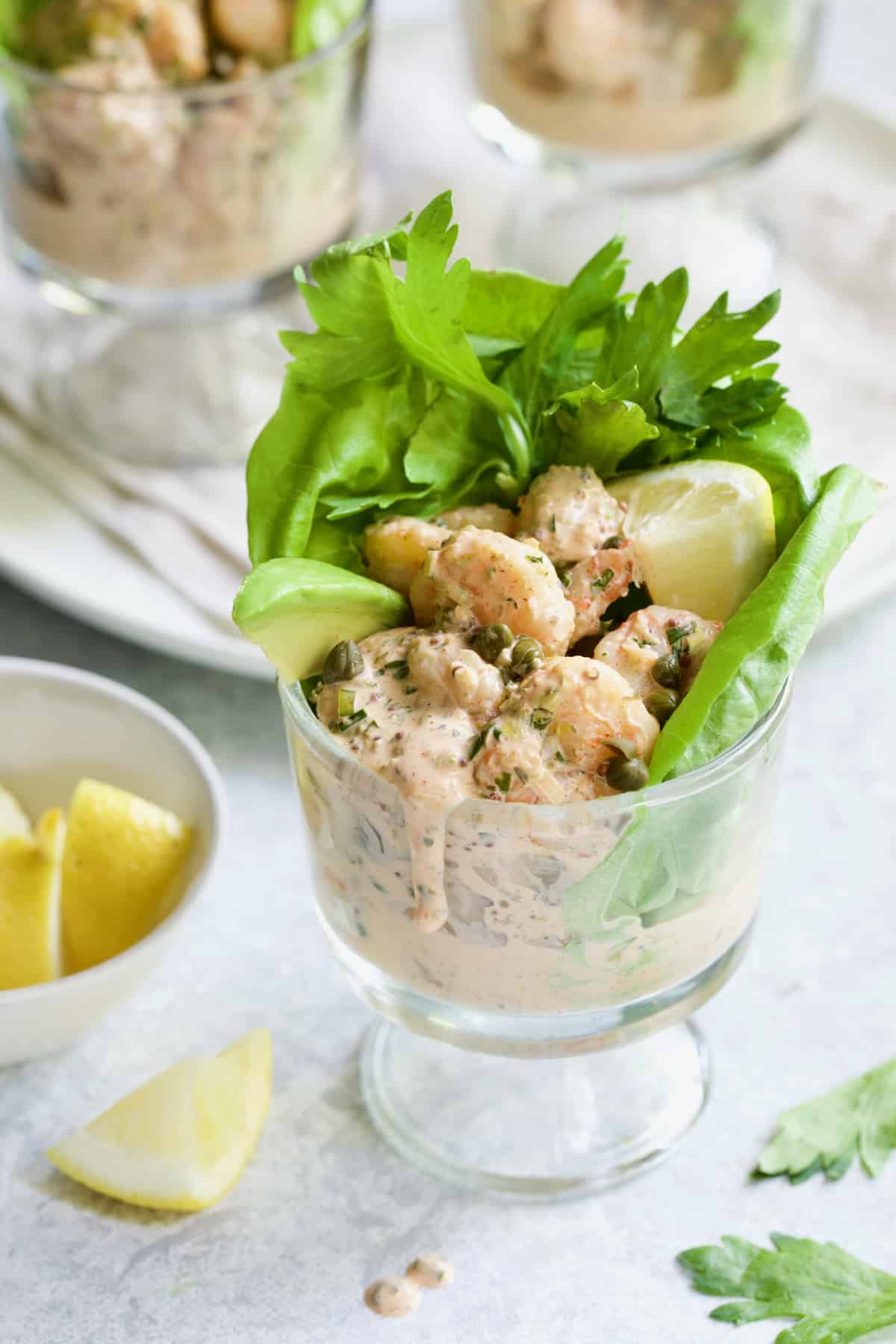 Sriracha Shrimp Remoulade Cocktail in footed glass with sauce dripping down the side.