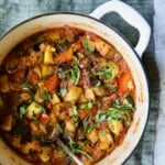 Classic French Ratatouille in white Dutch oven garnished with fresh basil.