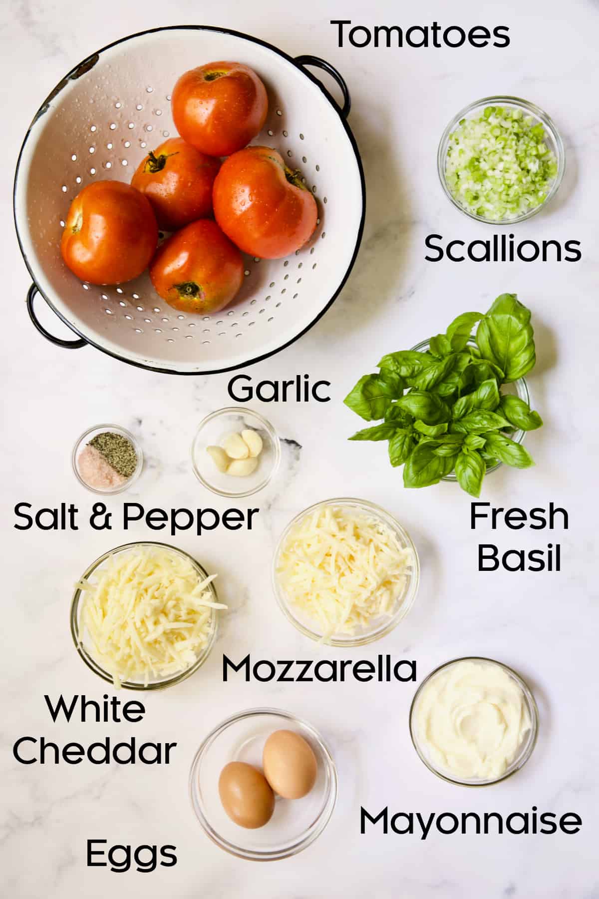 Ingredients for Crustless Southern Tomato Pie on white marble background.