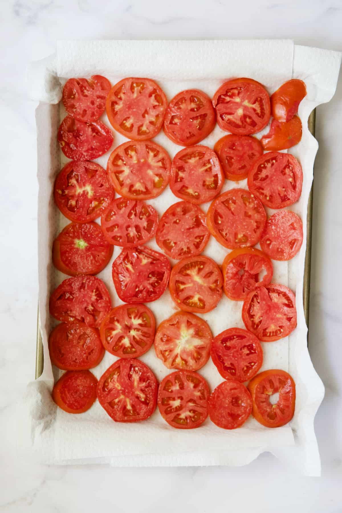 Tomato slices on paper towel-lined baking sheet.
