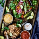 Grilled Tajin-Seasoned Chicken Fajitas on wood board with all the accompaniments.
