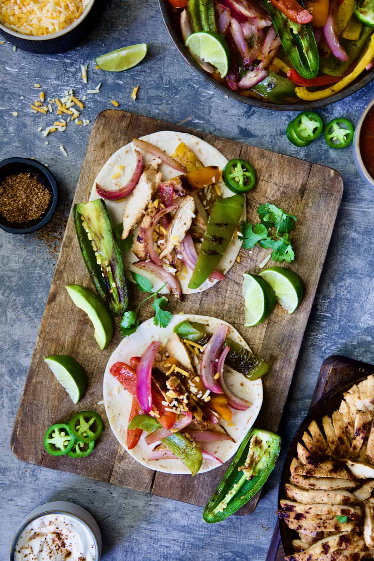 Grilled Tajin-Seasoned Chicken Fajitas assembled on wood cutting board.