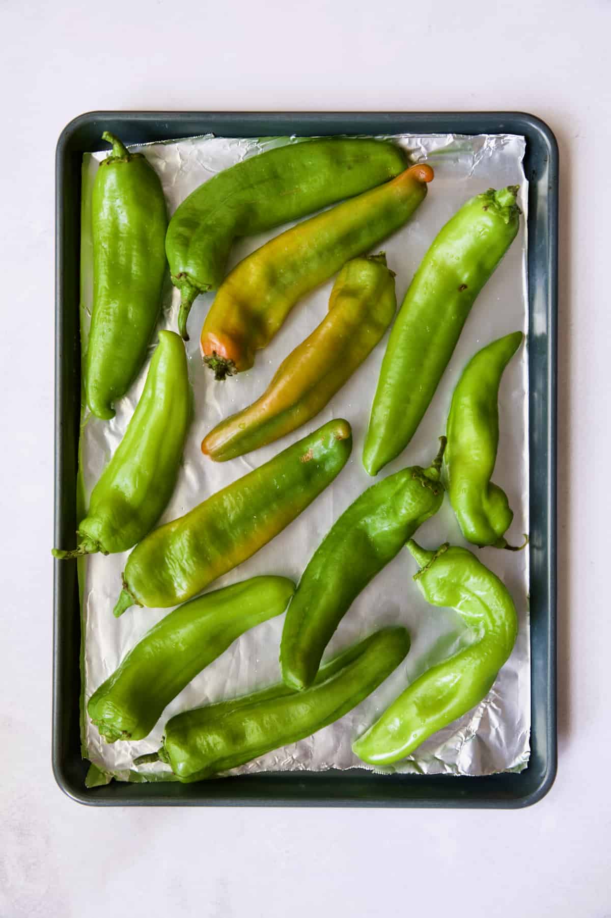 Hatch green chiles on rimmed sheet pan before being roasted.