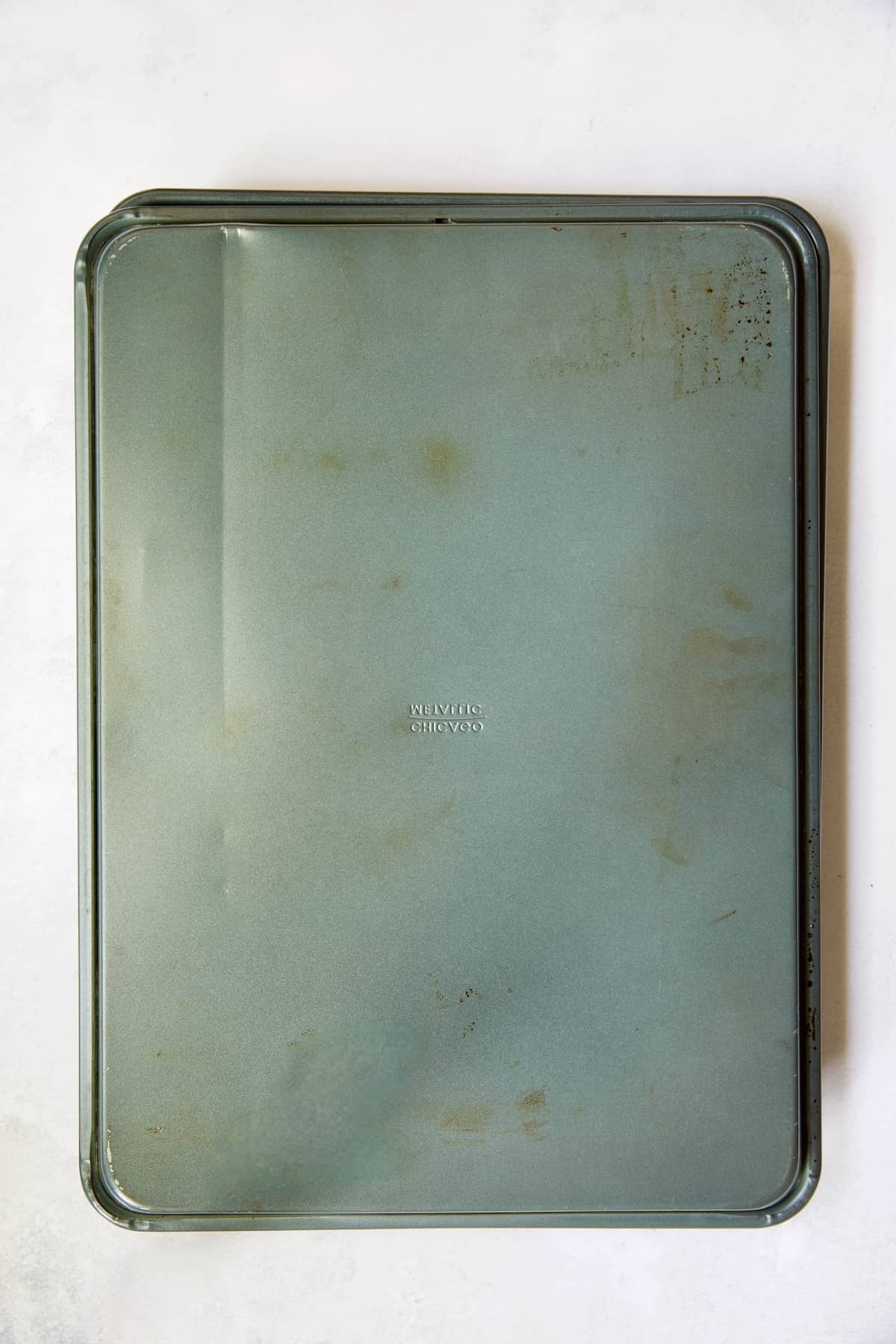 Two sheet pans with one flipped over to enclose Hatch green chiles.
