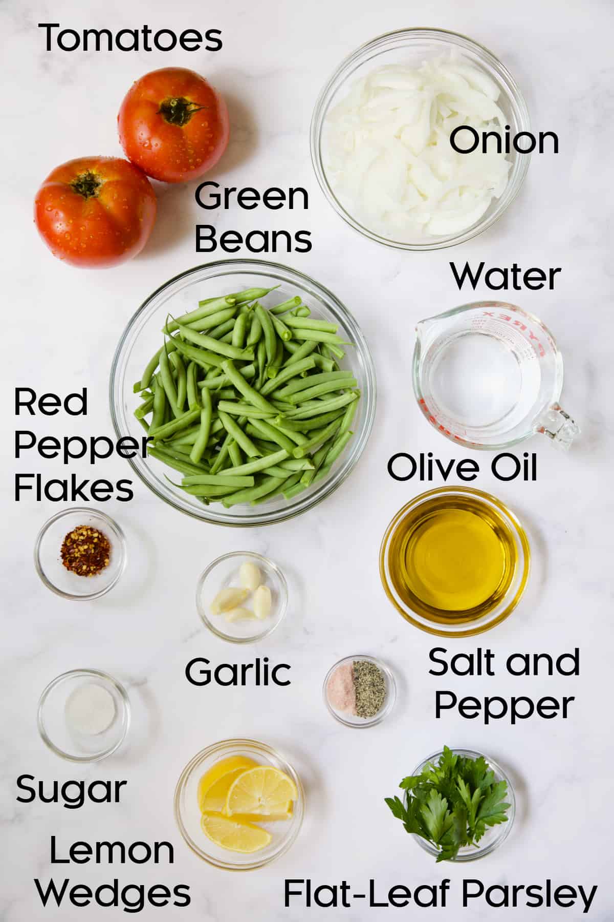 Ingredients for Mediterranean Braised Green Beans with Tomatoes in glass bowls.