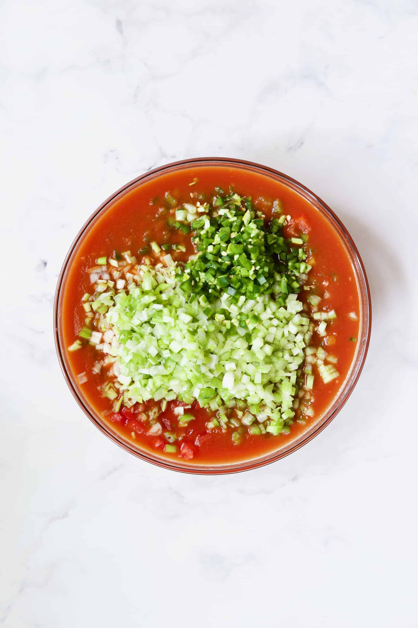 Ingredients for Very Veggie Gazpacho being combined in glass bowl.