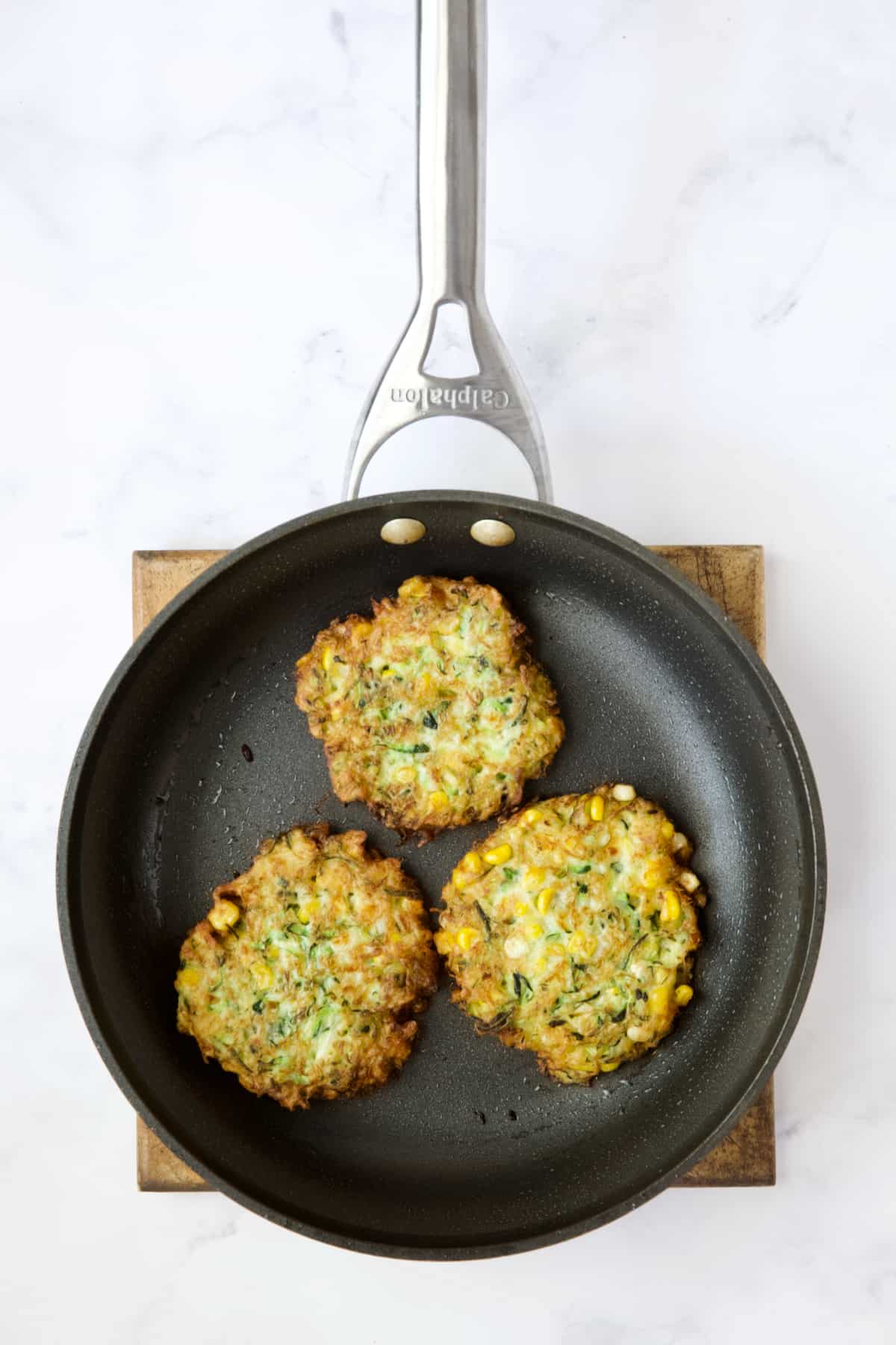 Three Zucchini Corn Fritters in nonstick skillet.