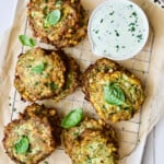 Zucchini Corn Cakes with Basil Buttermilk Sauce on cooling rack garnished with fresh basil.