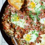Eggs in Purgatory with Italian Sausage in skillet with toasted bread.