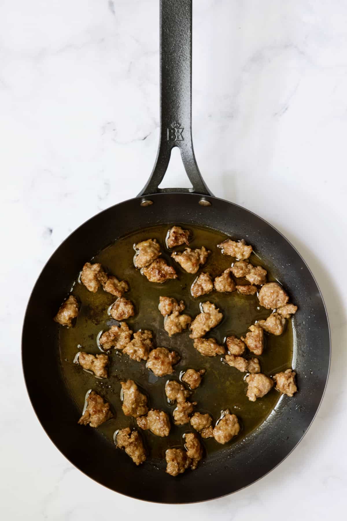 Cooked Italian sausage in black skillet.