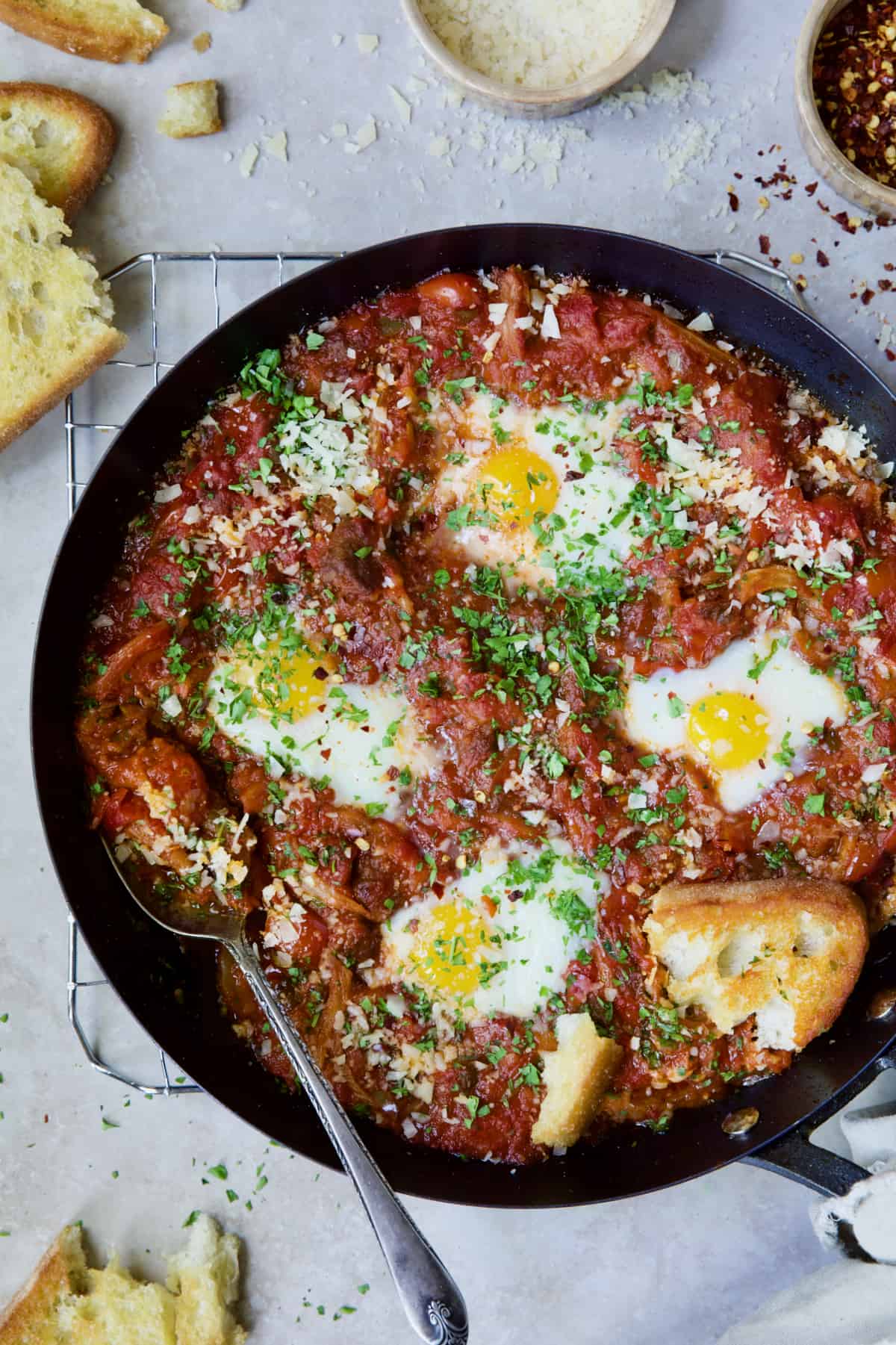 Eggs in Purgatory with Italian Sausage in skillet with serving spoon.
