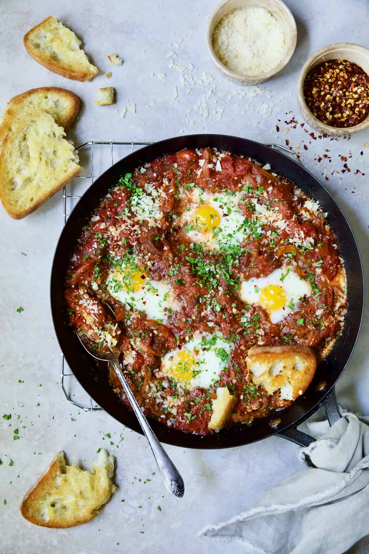 Eggs in Purgatory with Italian Sausage in skillet with broken toasted bread.