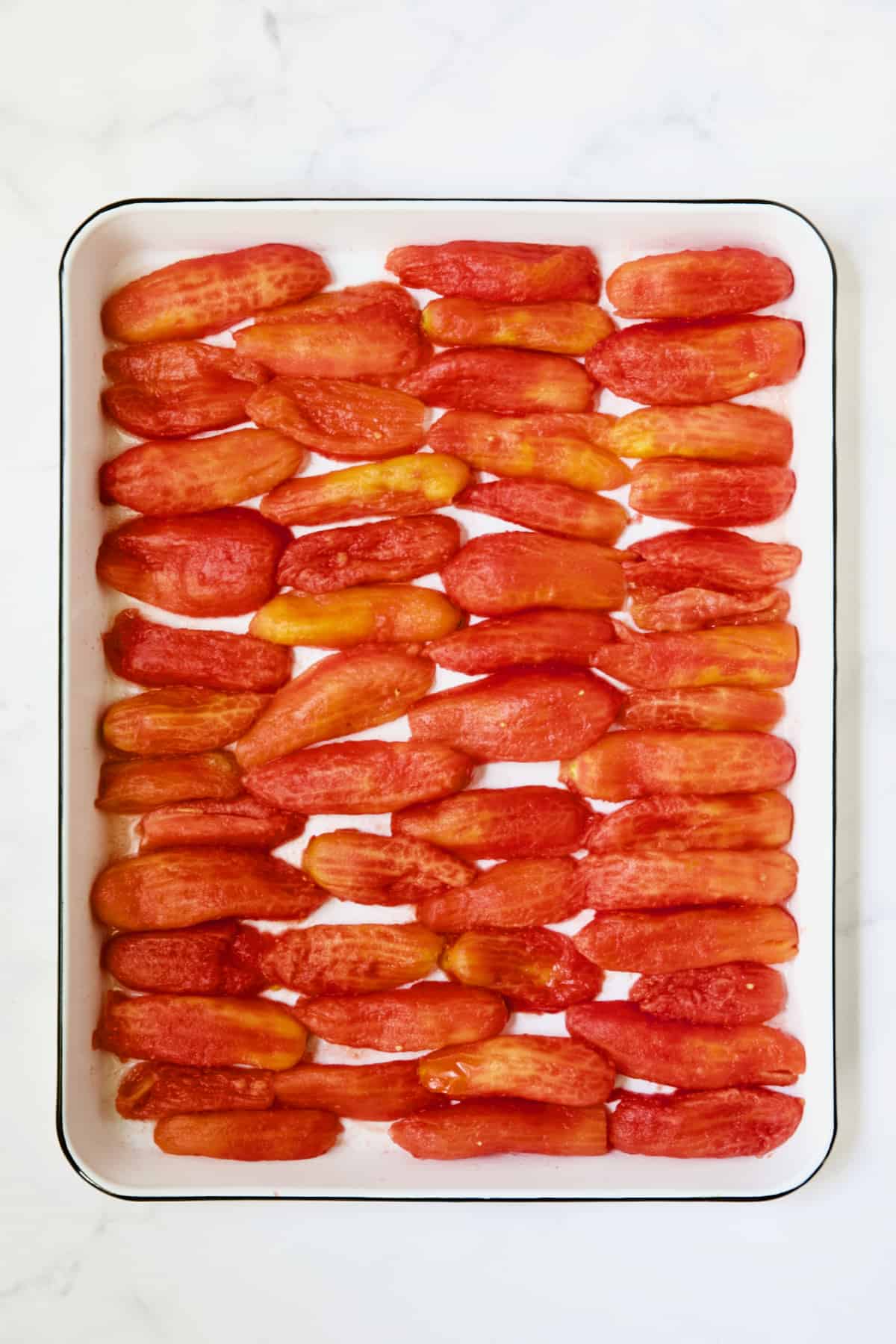 40 plum tomato halves on white enameled baking sheet.