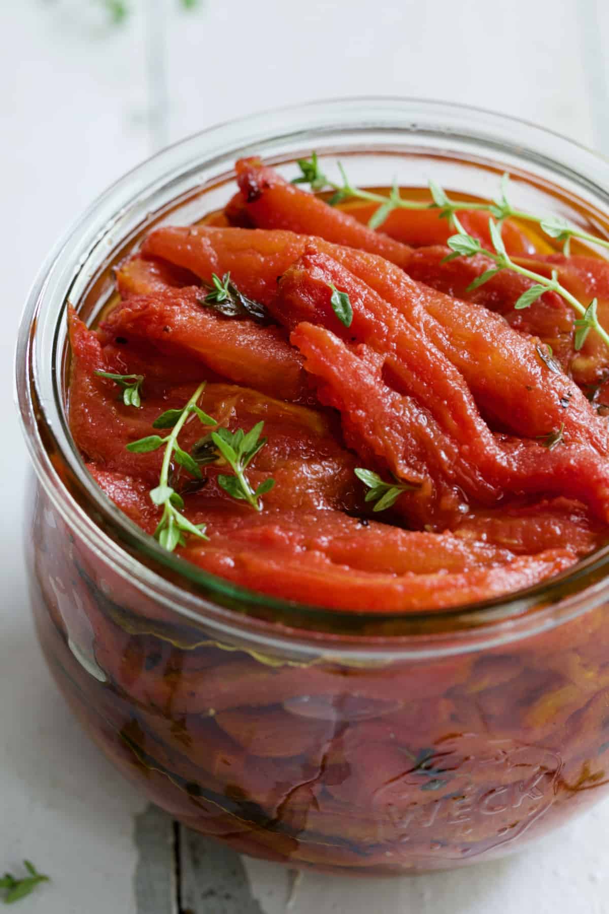 Tomato Confit in glass jar with thyme sprigs.