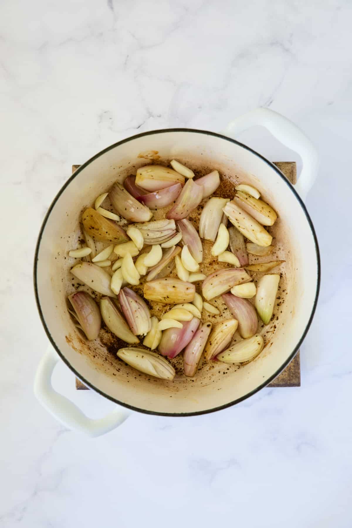 Shallots and garlic in white Dutch oven.