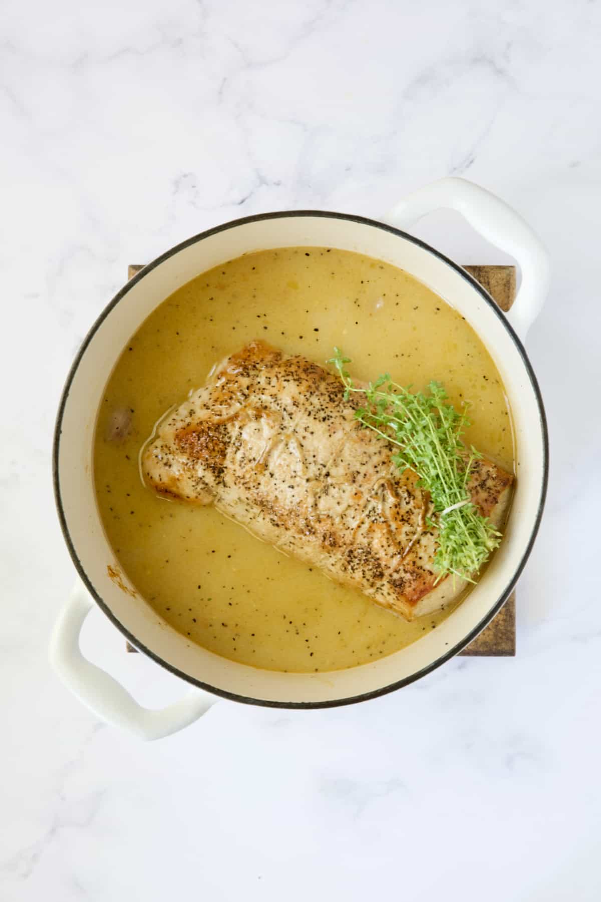 Braised Pork Loin Roast in Dijon Mustard Sauce in white Dutch oven.