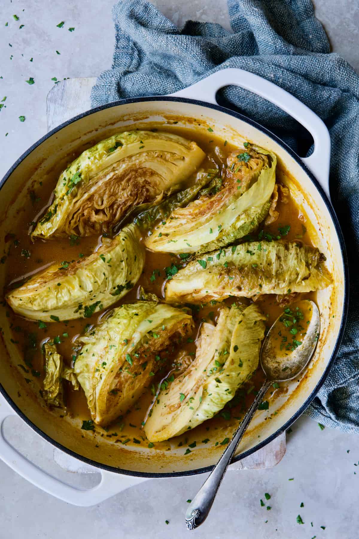 Cider Vinegar Braised Cabbage Wedges in white enamel cast iron skillet with blue napkin.