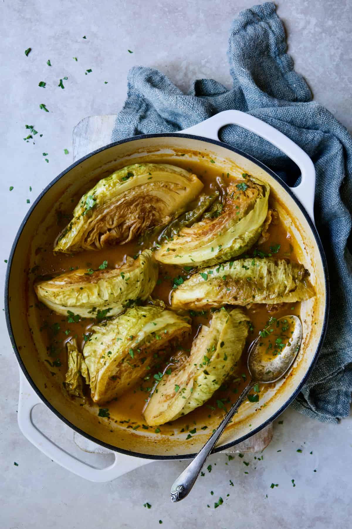Cider Vinegar Braised Cabbage Wedges in white cast iron skillet garnished with fresh parsley.