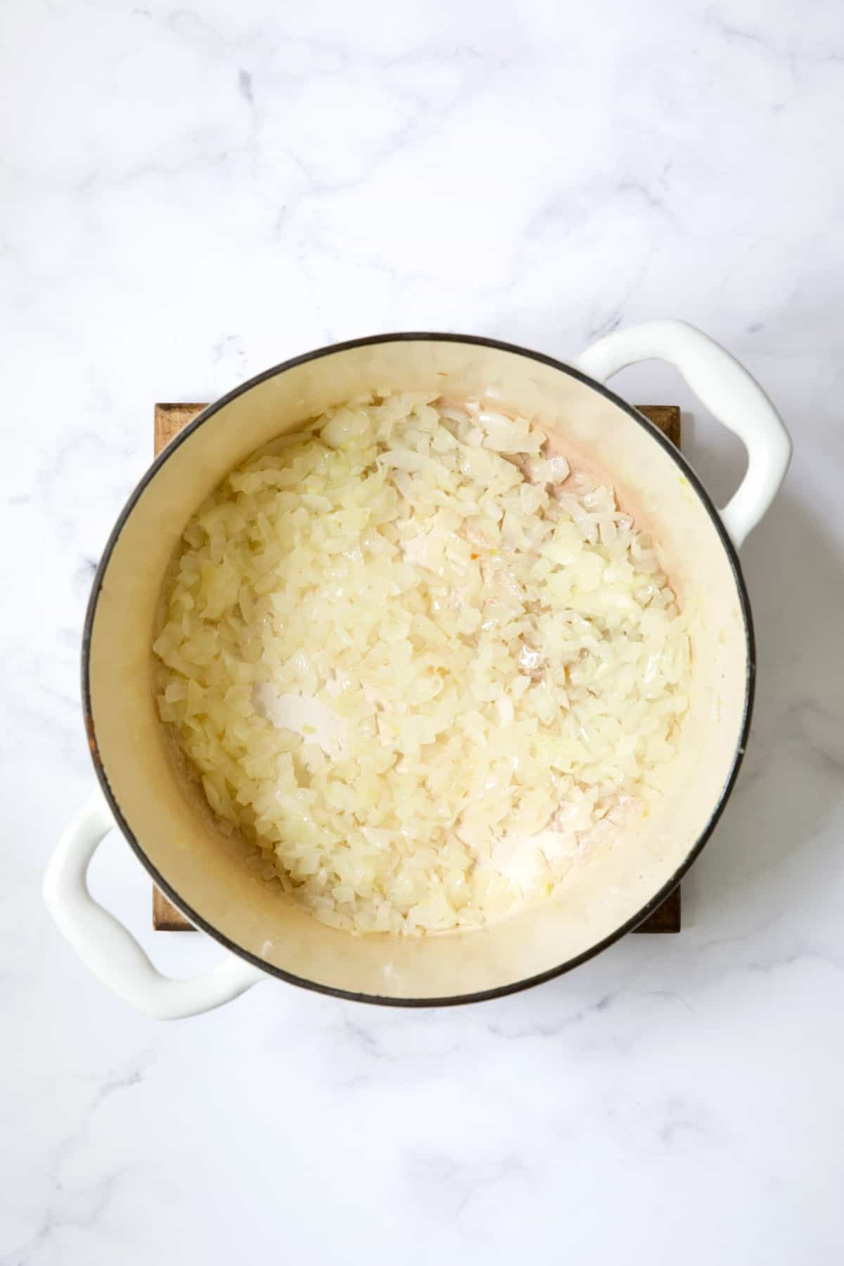 Cooked onion in white Dutch oven.