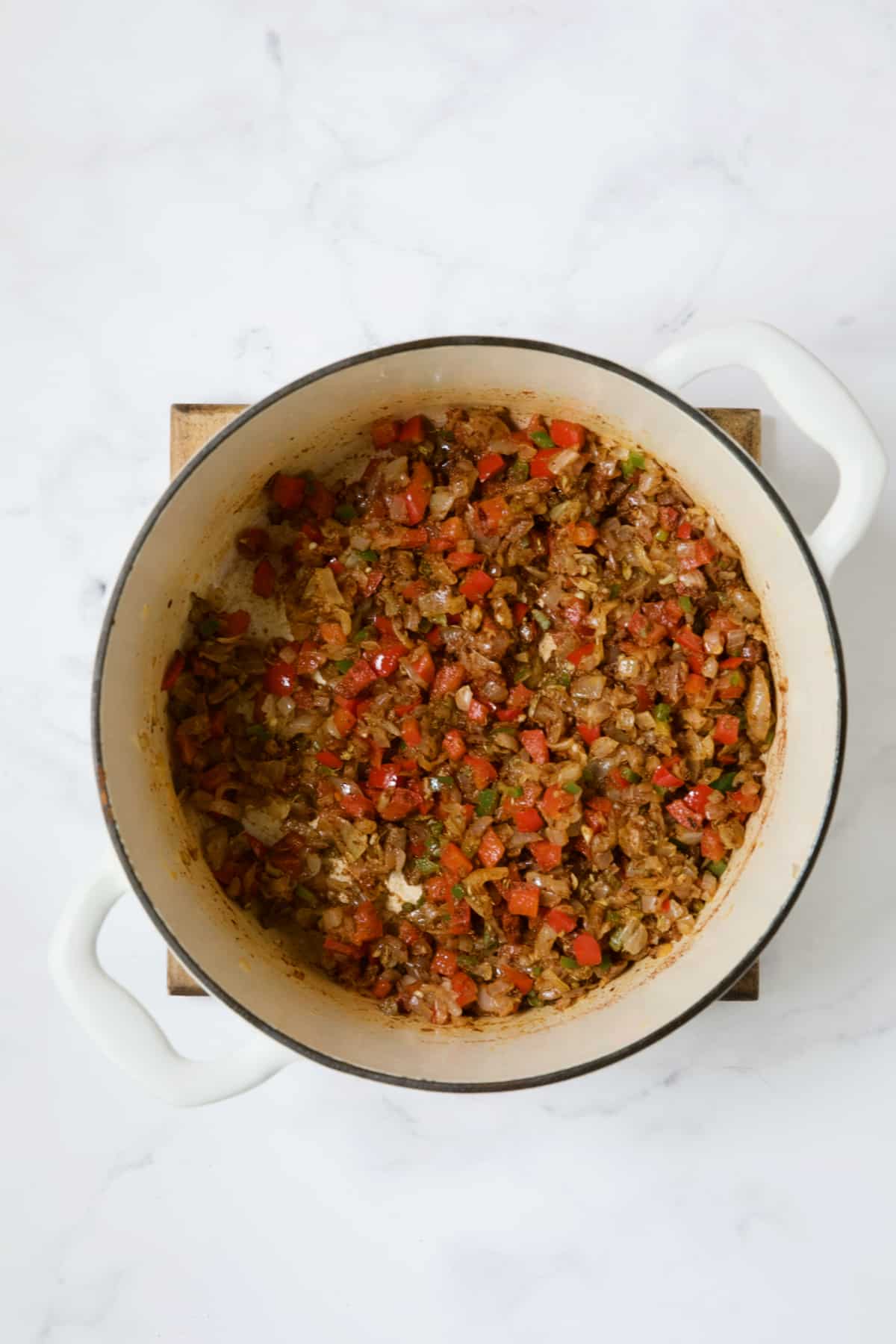 Vegetables with spice blend in white Dutch oven.