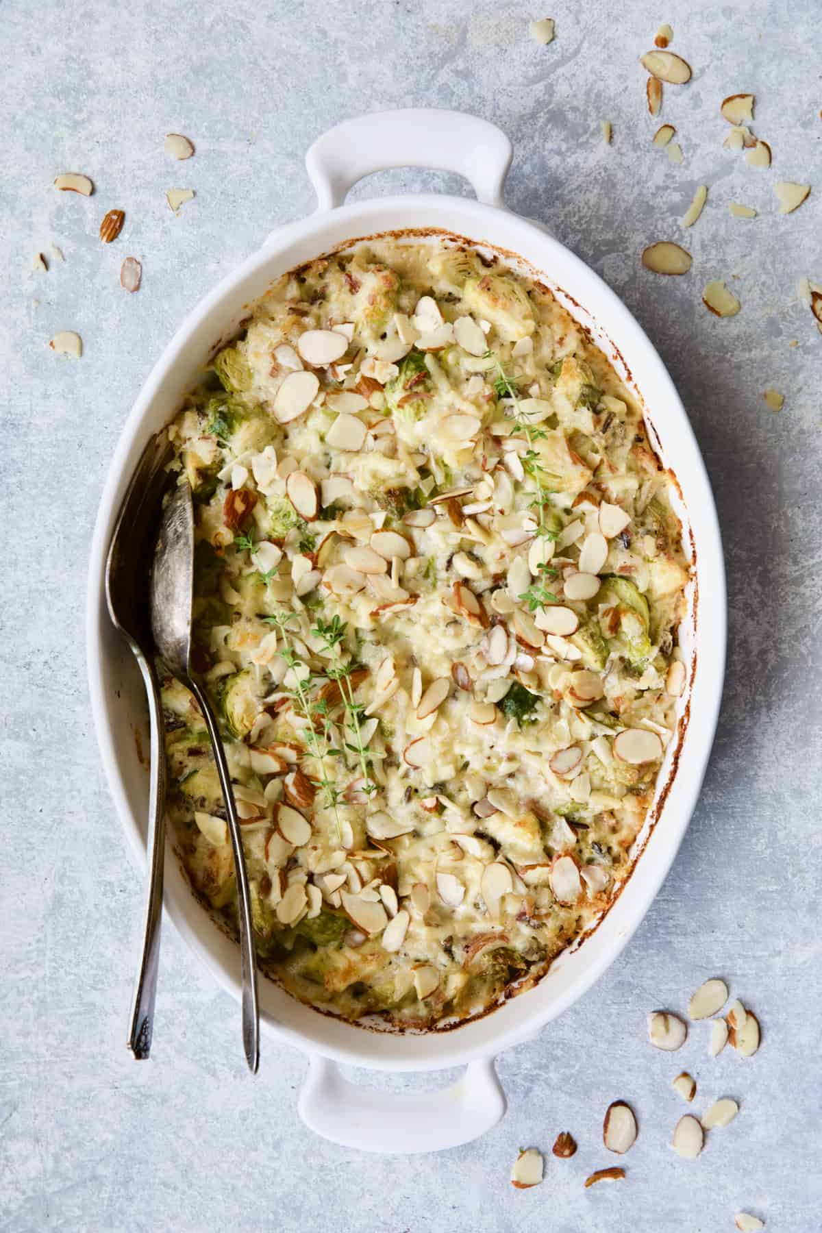 Cheesy Brussels Sprouts and Wild Rice Casserole with serving utensils.
