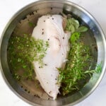 Turkey breast half in Easy Turkey Brine in stainless steel bowl.
