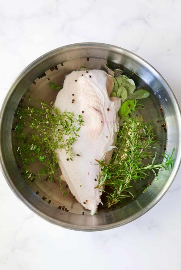 Turkey breast half in Easy Turkey Brine in stainless steel bowl.