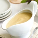 Gravy in white gravy boat on beige napkin.