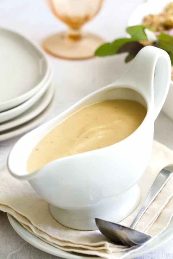Gravy in white gravy boat on beige napkin.