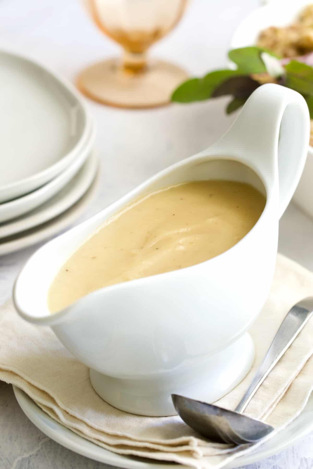 Gravy in white gravy boat on beige napkin.