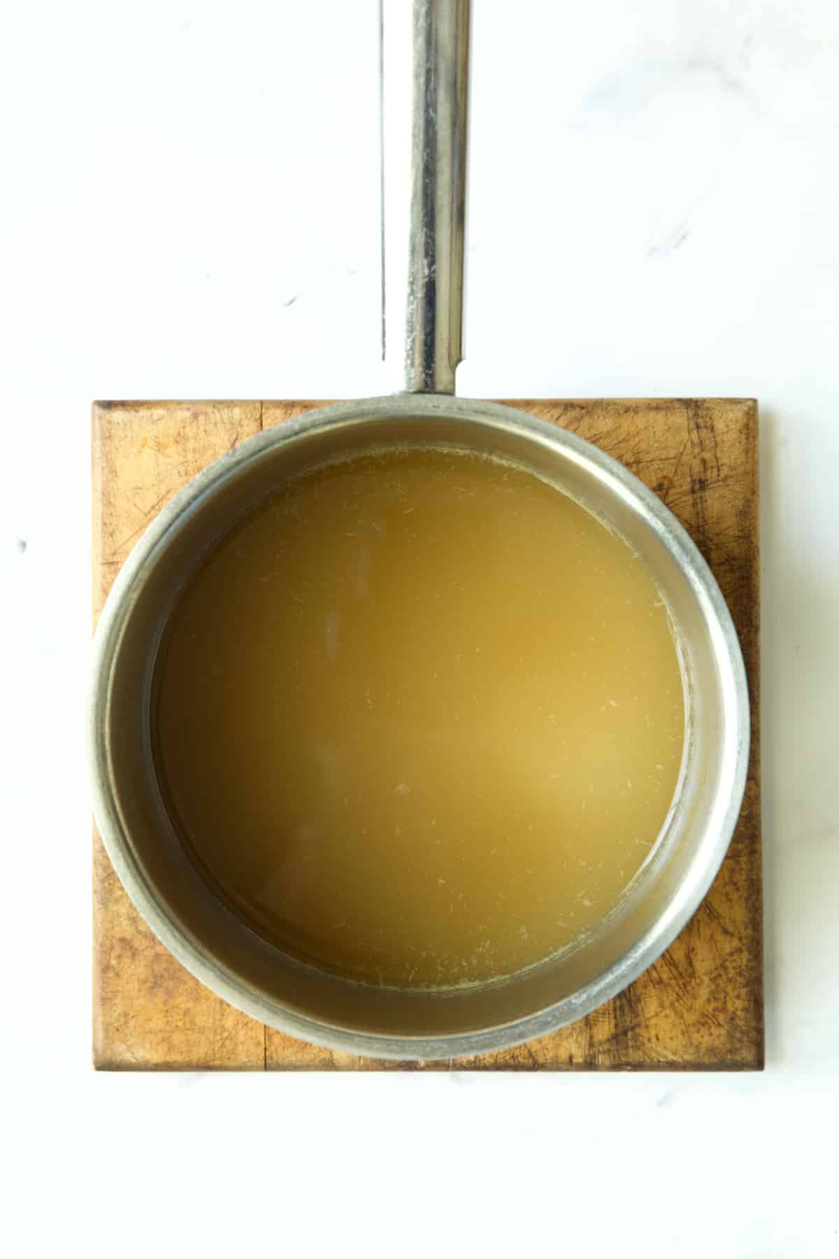 Reduced chicken broth in stainless steel saucepan.