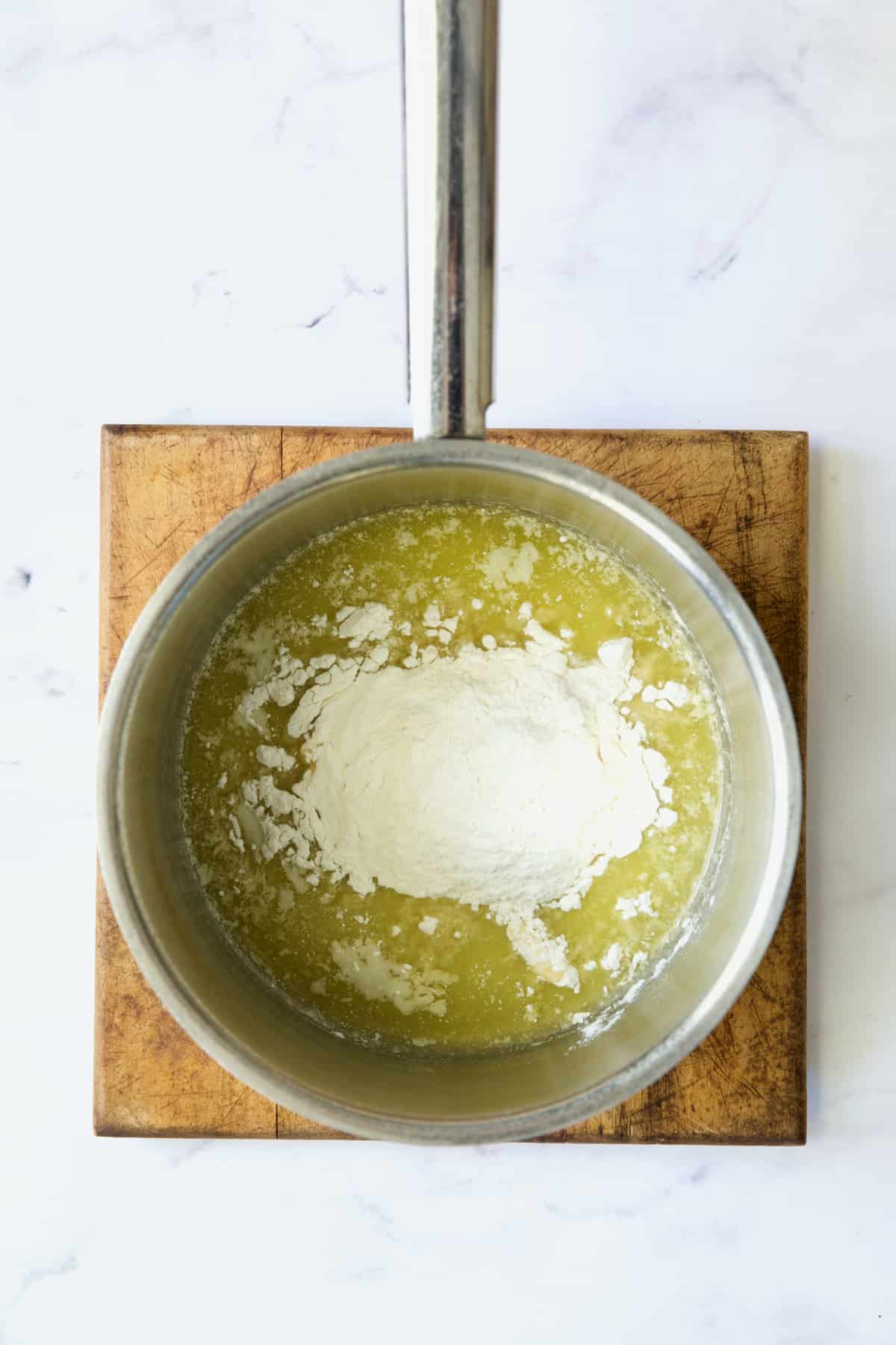 Flour added to melted butter in stainless steel saucepan.
