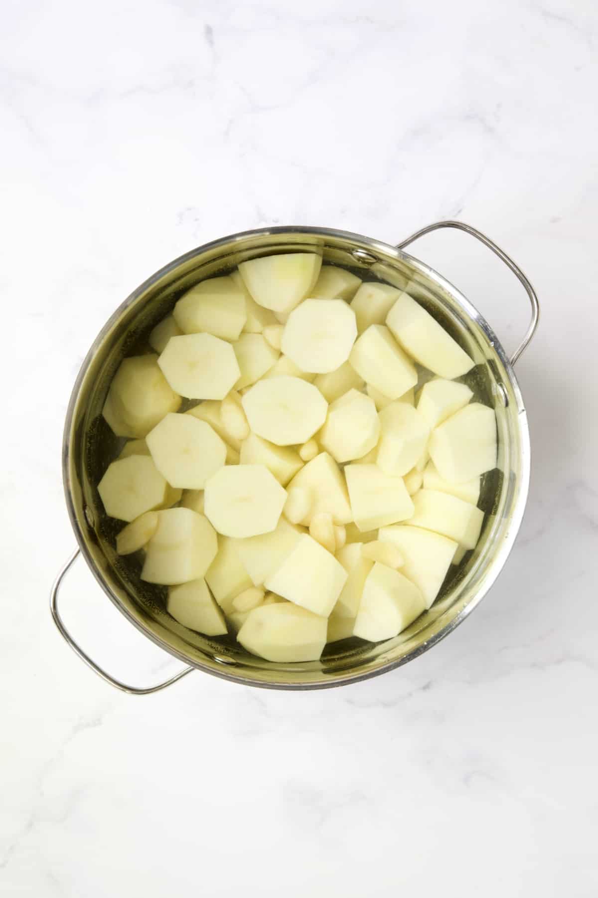 Potatoes in water in pot before being boiled.