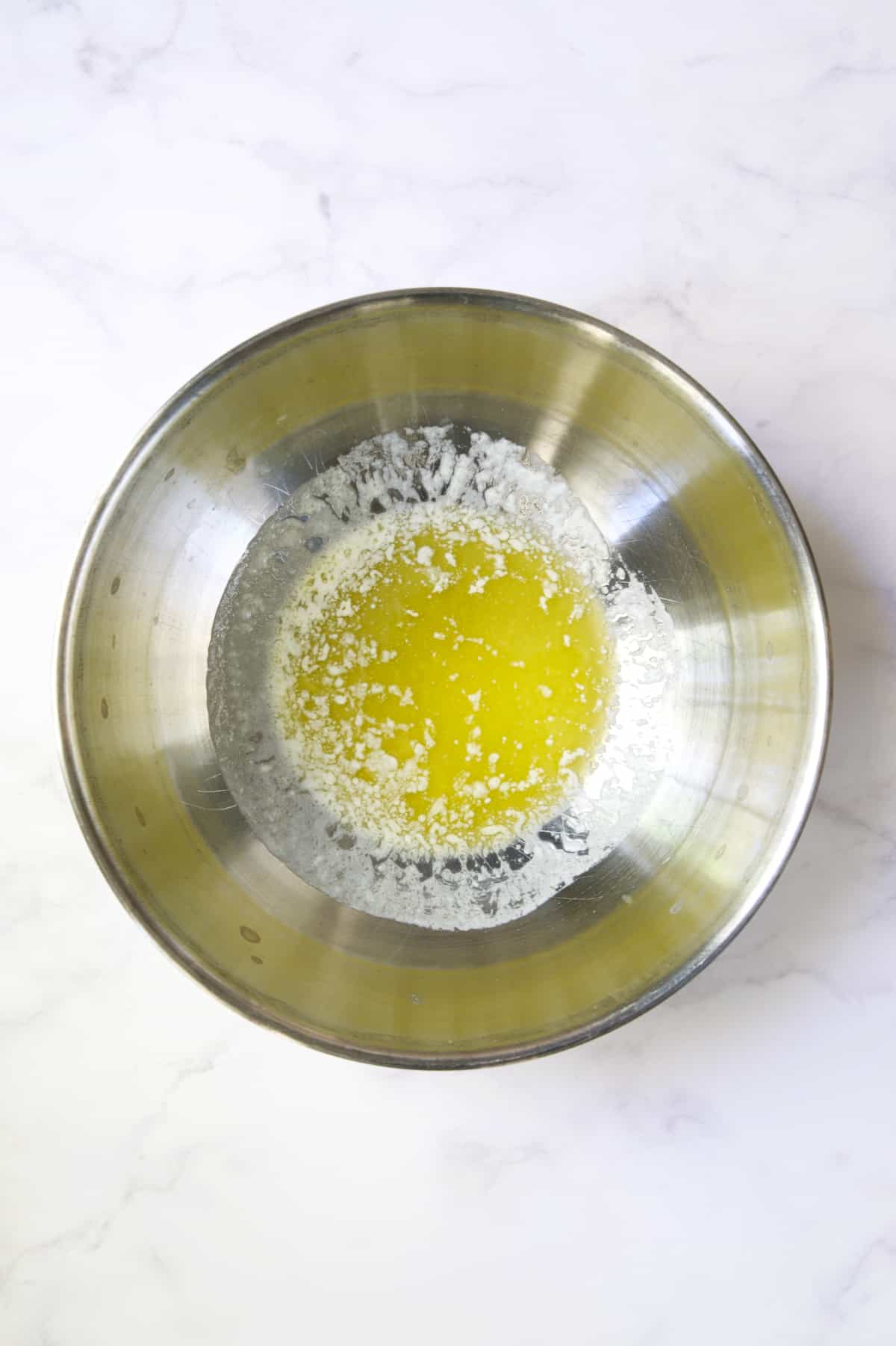 Melted butter in stainless steel bowl.
