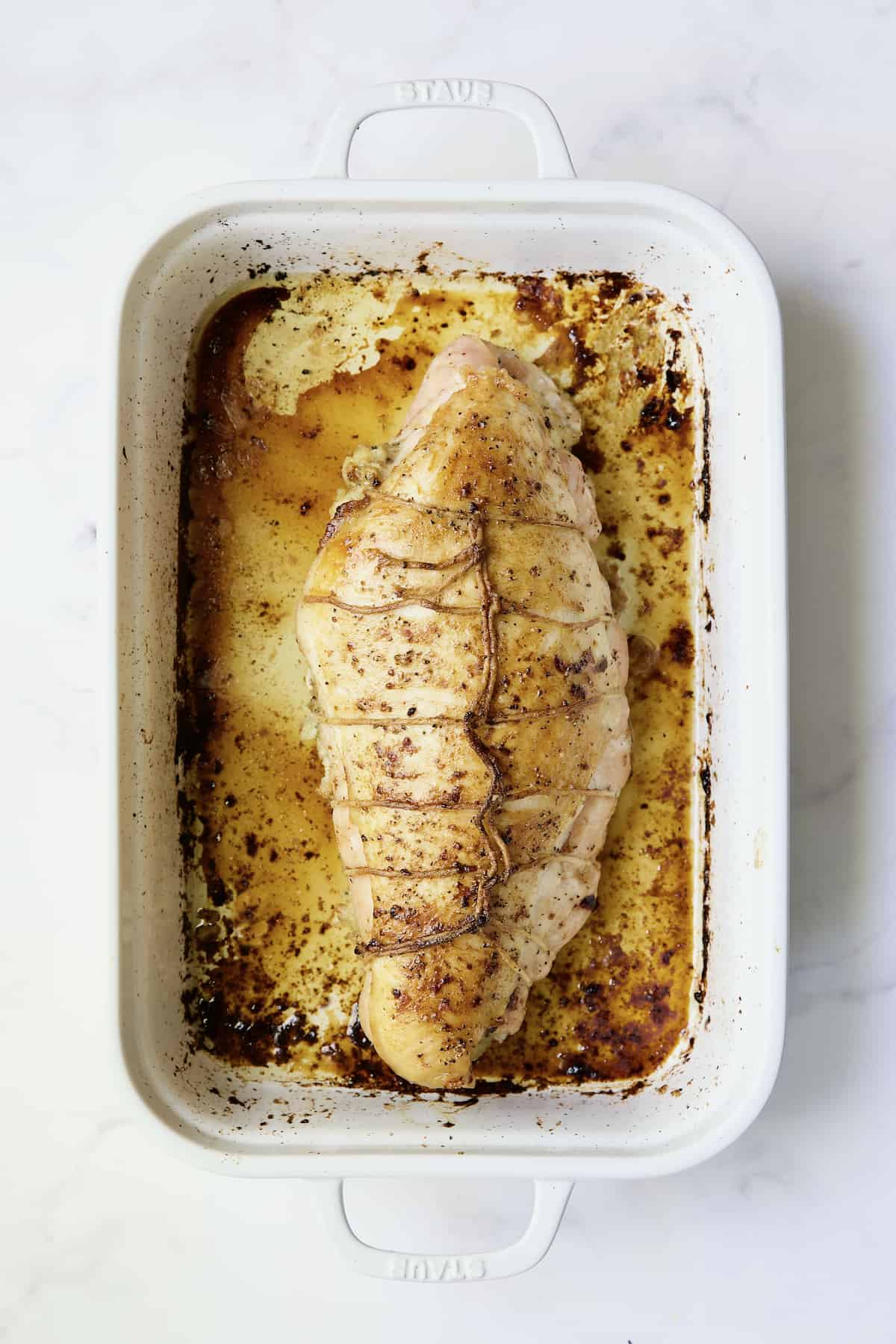 Roast Turkey Breast with Traditional Stuffing in white roasting pan.